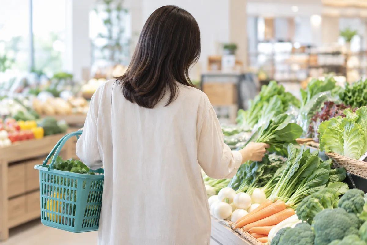 スーパーで野菜を選ぶ後ろ姿の女性
