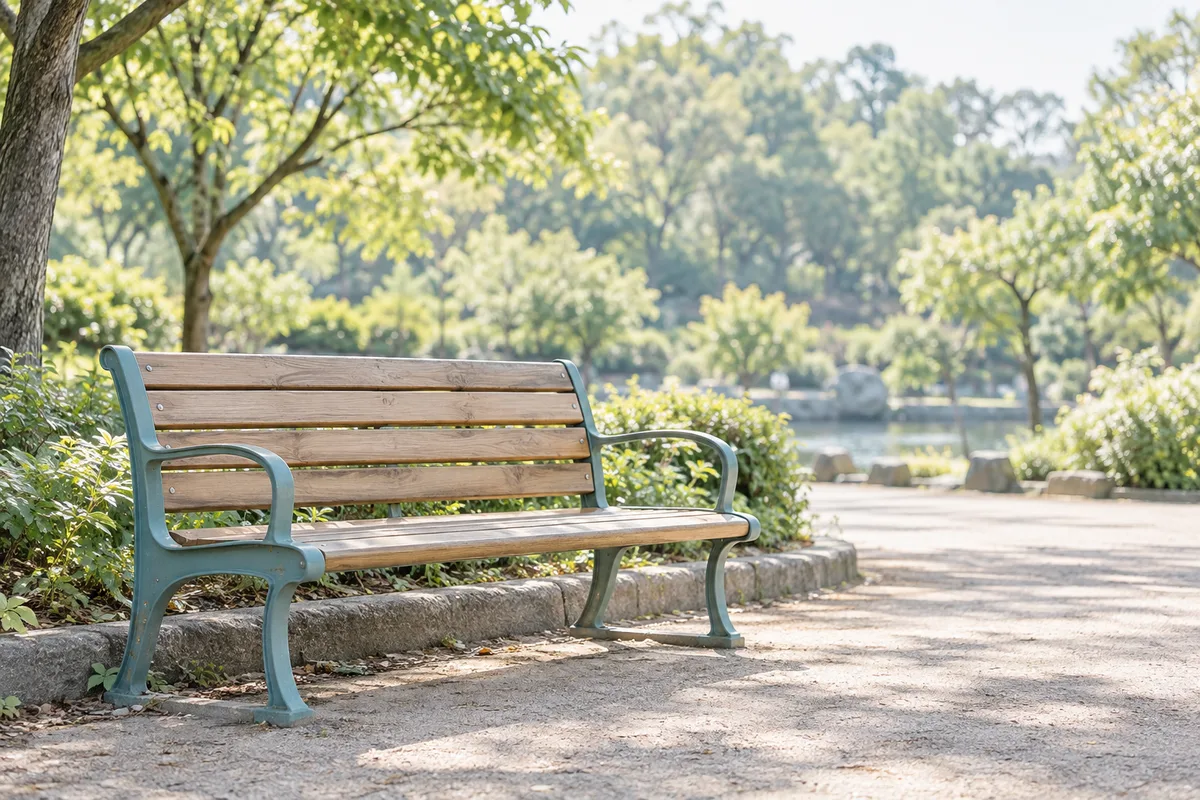朝の光が差す、公園の空いた木のベンチ